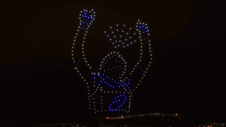 atleta levantando las manos, formadas por un enjambre de drones de espectáculo